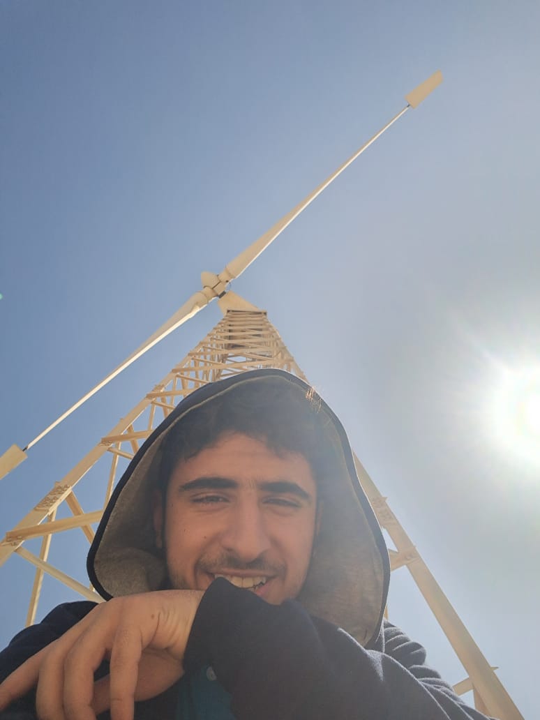 yusuf allam below a wind turbine in a wind farm